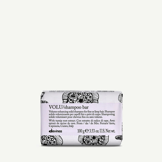 Davines VOLU Shampoo Bar, 100g, wrapped in white packaging with black floral patterns. Designed to add volume to fine or limp hair, this shampoo bar features turnip root extract from a farm in Caprauna, Italy.